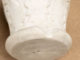 a white vase sitting on a table with a brown background