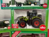 four toy tractors in a display case on a red table