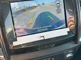a man that is sitting in the driver ' s seat of a car looking at the rear view mirror
