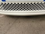 the front end of a white car with a blue stripe on it