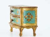 a small gold and blue chest of drawers on a stand