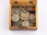 une petite boîte en bois remplie de pièces de monnaie posée sur une surface blanche
