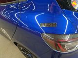 the rear end of a blue car with a sticker on it
