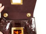 a person holding a brown purse with a gold handle