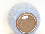 a blue vase with a brown lid on a white surface