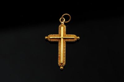 un pendentif en forme de croix en or sur fond noir