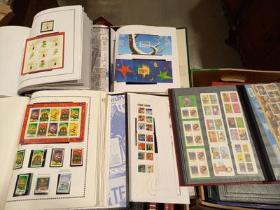 de nombreux timbres posés sur une table, à côté d'un livre ouvert