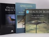 trois livres consacrés à différents oiseaux, exposés sur une surface blanche