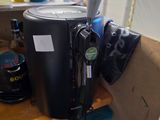 une cafetière noire posée sur une étagère en bois, à côté d'un vase de fleurs