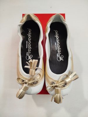 une paire de chaussures blanches et dorées ornées d'un nœud doré, présentée dans une boîte rouge