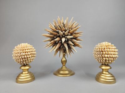 trois vases en or ornés de coquillages, posés sur une table