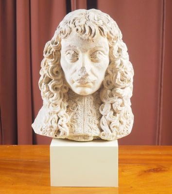 buste en marbre représentant un homme aux cheveux bouclés, posé sur une table en bois