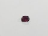 a close up of a red garnet stone on a white surface