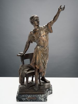 statue en bronze représentant une femme assise sur une chaise, le bras levé
