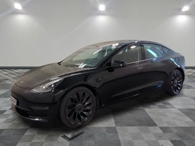 une Tesla Model 3 noire garée sur un sol à damier