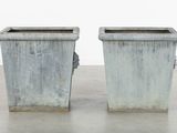 two cement planters sitting on a concrete floor
