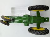 a green toy tractor with yellow wheels on a white surface