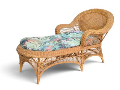the wicker chaise is made of rattan and has a tropical print cushion