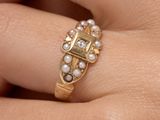a woman ' s hand holding a gold ring with pearls on it