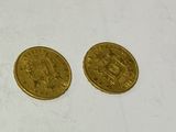 two gold coins sitting next to each other on a white surface