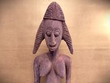 a wooden statue of a woman with a hat on her head