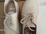 pair of white leather shoes with laces on top of a cardboard box