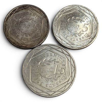 three silver coins sitting on top of each other on a white surface