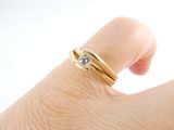 a woman ' s hand with a gold ring and a diamond on it