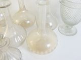 Plusieurs vases en verre sont alignés sur une surface blanche