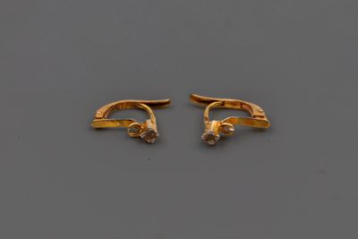 une paire de boucles d'oreilles en or serties de diamants sur un fond gris