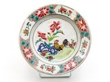 une assiette sur laquelle sont peints un coq et des fleurs