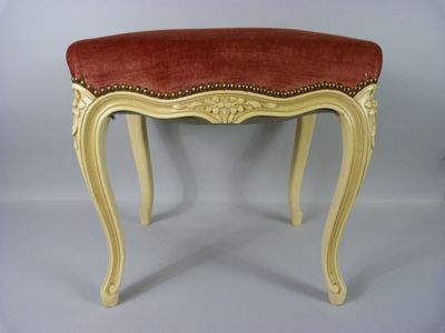 un banc rouge et blanc avec des finitions dorées et un coussin d'assise rouge