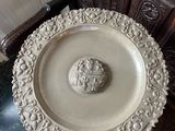 une assiette blanche ornée d'une tête de lion, posée sur une table en marbre