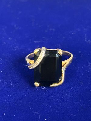 a close up of a black stone ring on a blue surface