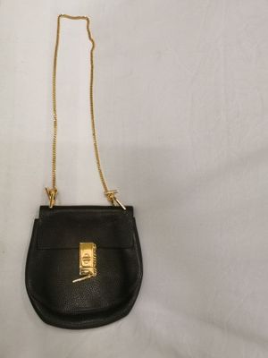 un petit sac à main noir auquel est accrochée une chaîne dorée