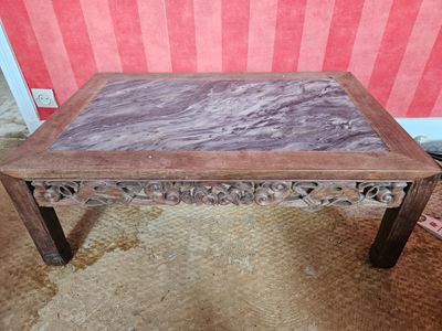 une table au plateau en marbre posée sur un sol recouvert de moquette