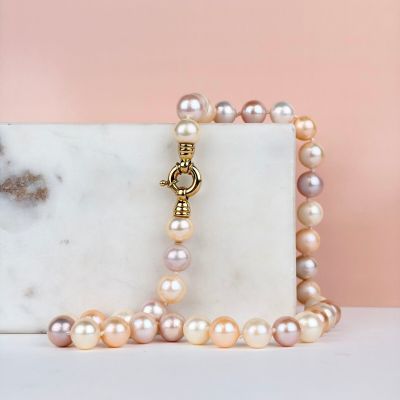 a close up of a necklace with pearls on a marble block