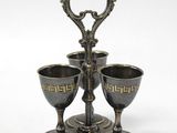 a silver plate with three cups on it on a stand