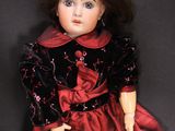 an old doll with a red dress and black shoes on a black background