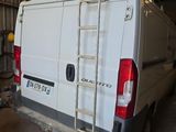 une camionnette blanche garée dans un garage, avec une échelle à l'arrière