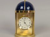 a gold clock with a blue glass dome on top