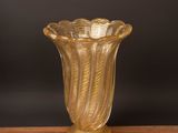 gold glass vase sitting on a wooden table against a black background