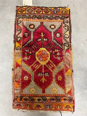 an old rug hanging on a wall with a wooden hanger