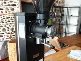 a black coffee grinder on a wooden table in a kitchen