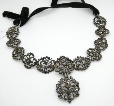 un gros plan d'un collier posé sur une surface blanche, avec un ruban noir