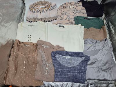 une valise remplie de vêtements et des vêtements posés par terre