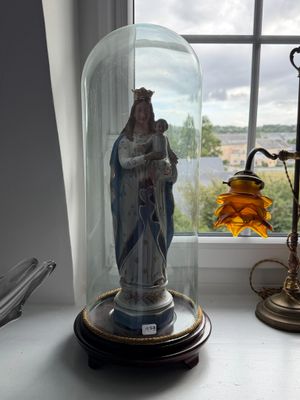 une statue représentant une femme, placée sous un dôme de verre sur le rebord d'une fenêtre