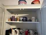 many cups and mugs on the shelves in the kitchen