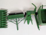 a green toy tractor with a trailer and a raker