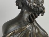 an antique bronze statue of a woman with a flower in her hair